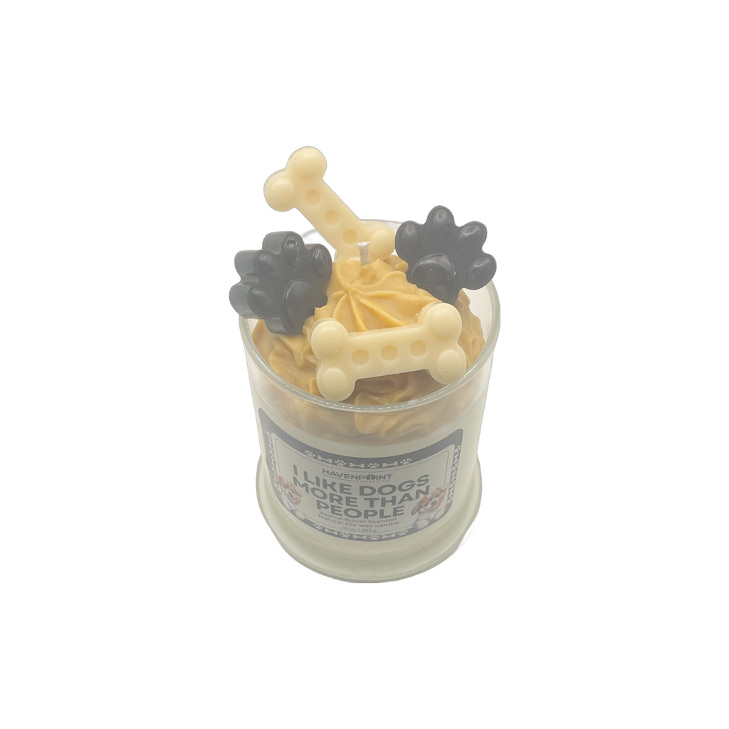 Candle with dog bone and paw print designs in a glass container on a white background
