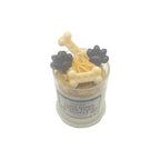 Candle with dog bone and paw print designs in a glass container on a white background