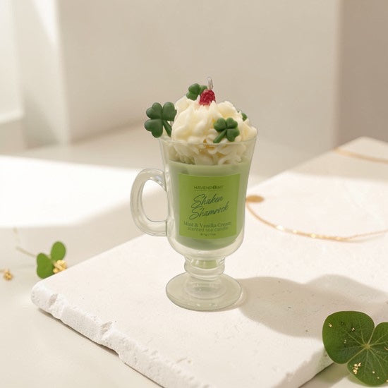 Green milkshake with whipped cream and clover leaves on a white surface