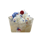 Ice cream sundae with whipped cream, berries, and colorful sprinkles in a clear bowl on a white background