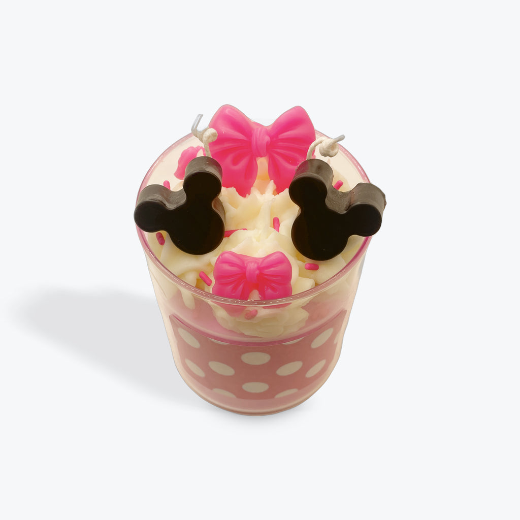 Candle shaped like a cup with polka dot design and bow decorations on a white background