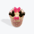 Candle shaped like a cup with polka dot design and bow decorations on a white background